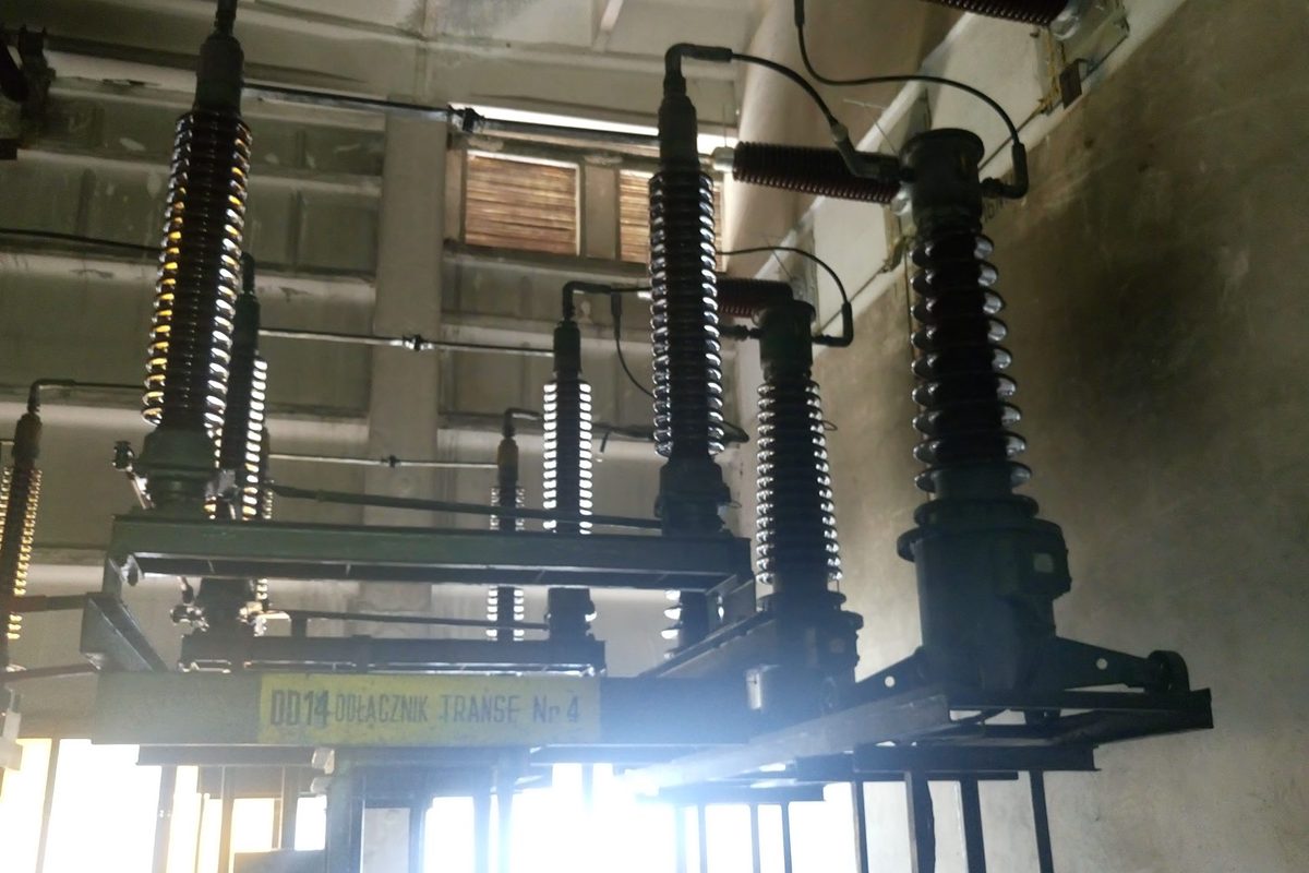 Pole transformatora 110 kV przed przebudową: odłączniki z napędami i izolatory wsporcze starego typu, obwody wtórne prowadzone w szafkach kablowych na terenie stacji. Stan zinwentaryzowany przez OPA-LABOR na potrzeby projektu.